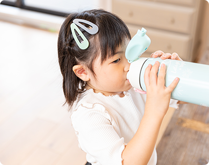 写真:水筒で飲み物を飲む女の子